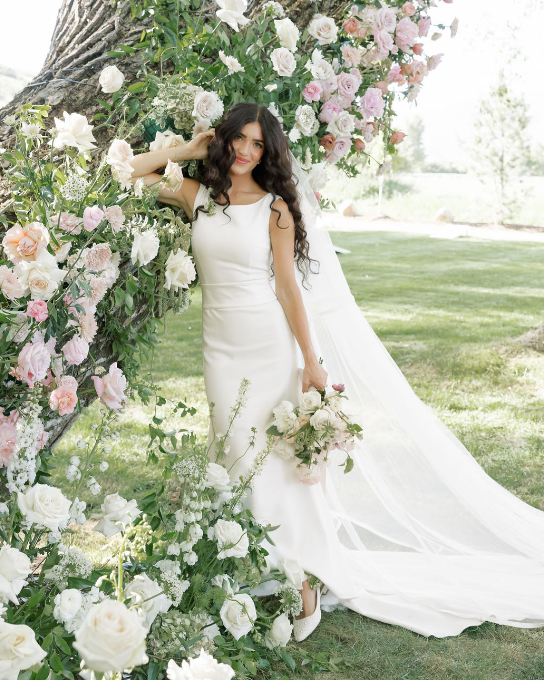 Bride holding blush bridal bouquet with a gorgeous tree truck floral installation