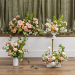 Four sympathy floral arrangement display featuring a large arch and multiple bouquets in soft peach, pink, cream, and white tones.