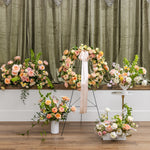 A sympathy floral arrangement display featuring a large arch and multiple bouquets in soft peach, pink, cream, and white tones.