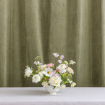 A wedding floral arrangement in a white ceramic vase.
