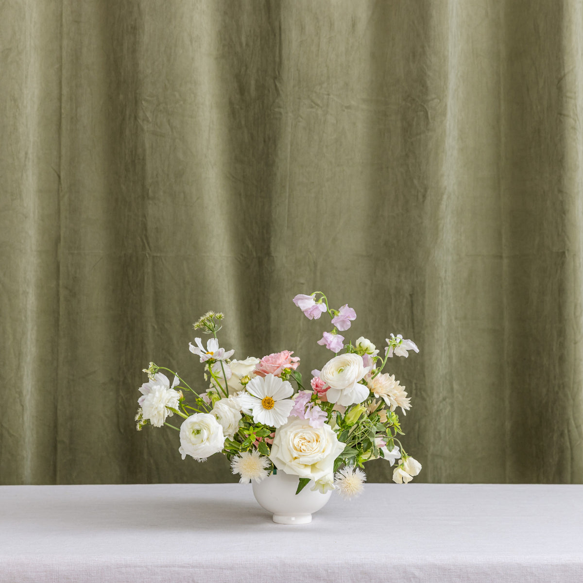 A wedding floral arrangement in a white ceramic vase.