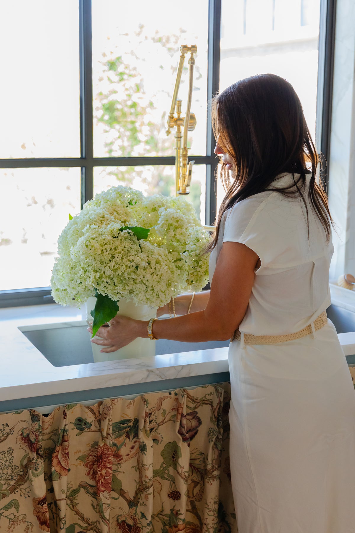 Florist Shawn Bailey holds hydrangea flower arrangement in a laundry room