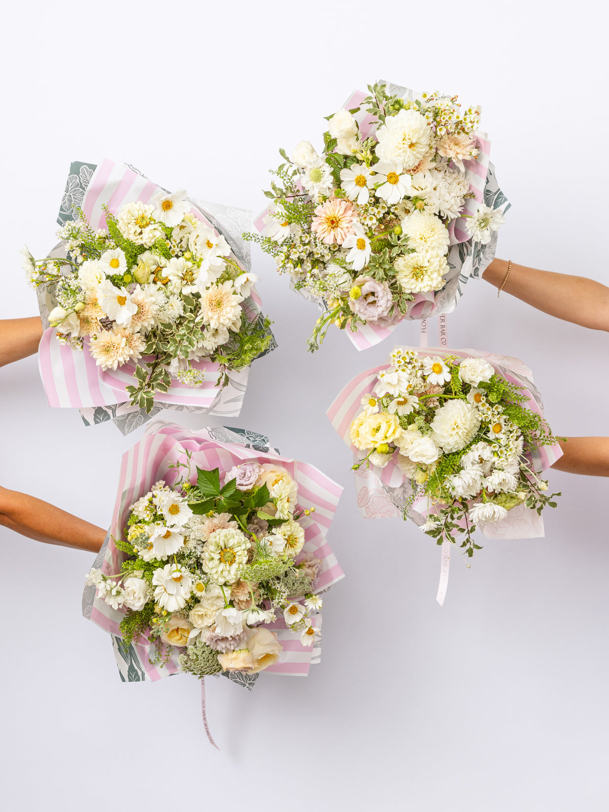 hands holding flower bouquets in whites and neutral florals