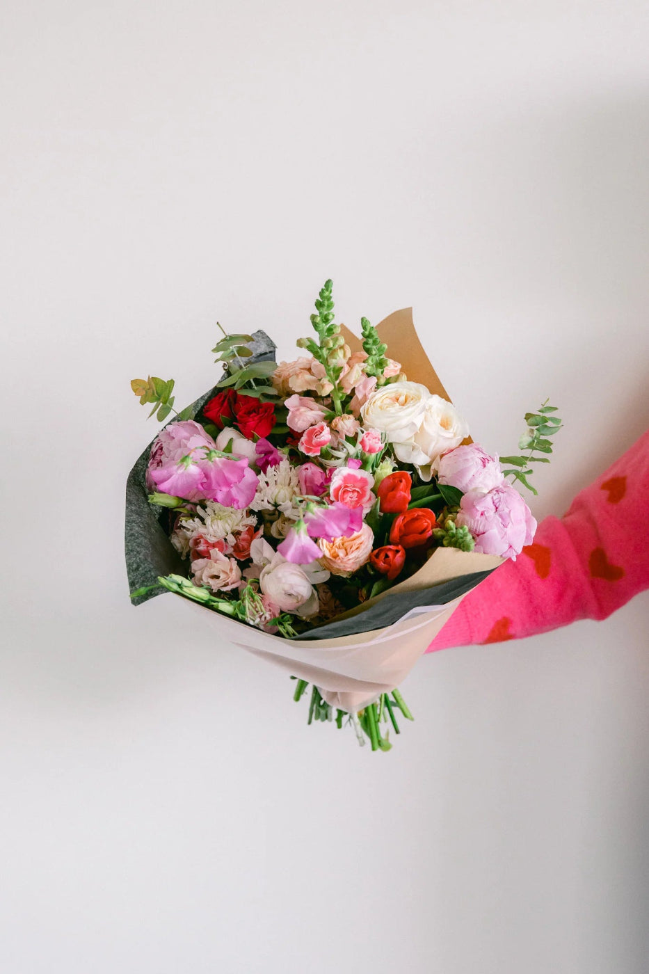 hand tied wrapped bouquet of red, pink and white flowers